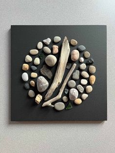 rocks and driftwood are arranged in a circle on a black slate board with white paint