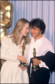 two people holding their oscars and posing for the camera