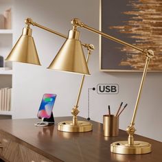 a desk lamp sitting on top of a wooden table next to a phone and pen holder