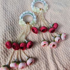 three pairs of earrings with flowers and pearls hanging from them on top of a blanket