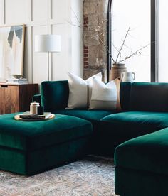 a living room filled with green couches and pillows in front of a large window