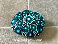 a blue and white painted rock sitting on top of a tile floor next to a wall