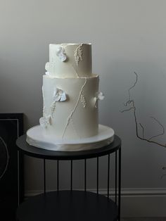 a three tiered white cake sitting on top of a table next to a vase