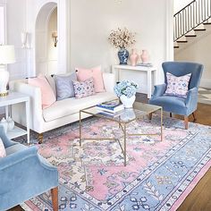 a living room filled with furniture and a chandelier hanging from the ceiling over a rug