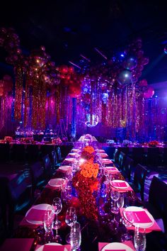 a long table is set up for a party with balloons and streamers hanging from the ceiling