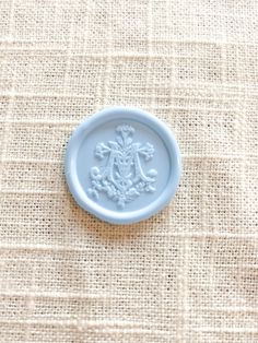 a small blue plate sitting on top of a cloth covered tablecloth with an ornate design in the center