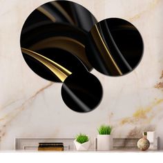 three black and gold circles on a white marble wall next to a plant in a vase