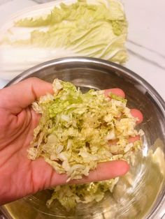 a person is holding up some food in a bowl on the counter top next to lettuce