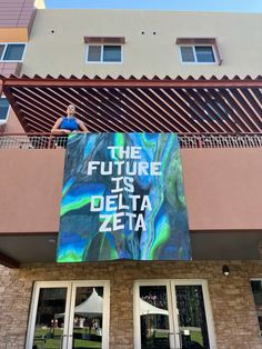 a man standing on top of a balcony next to a sign that reads the future is delta zeia