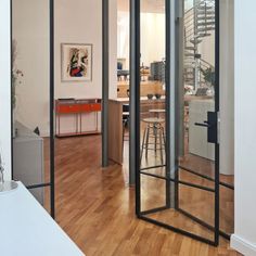 an open living room with wooden floors and glass doors that lead to the dining area