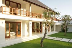 a large white house sitting on top of a lush green field next to a palm tree