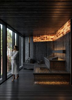 a woman in a bathrobe standing on a wooden floor next to a window