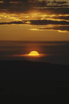 the sun is setting behind some clouds in the sky