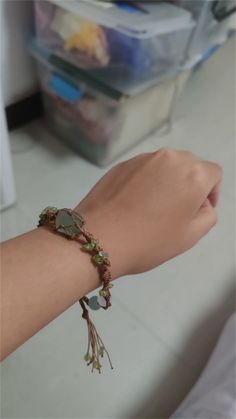 a woman's arm wearing a bracelet with flowers and leaves attached to the wrist