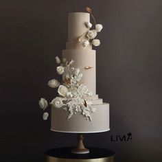 a three tiered wedding cake with white flowers on top and gold trimmings