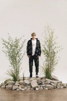 a man standing on top of a pile of rocks next to tall grass and plants