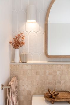 a white toilet sitting next to a bathroom sink under a mirror and a wooden tray