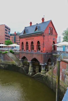 an old red brick building next to a body of water