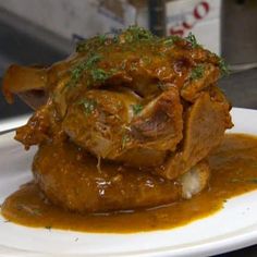 a white plate topped with meat covered in gravy