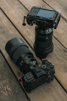 a camera sitting on top of a wooden floor next to a lens and a phone