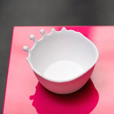 a white bowl sitting on top of a pink table