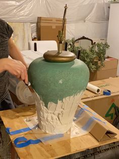 a woman is making a vase out of clay and paper maching it with scissors