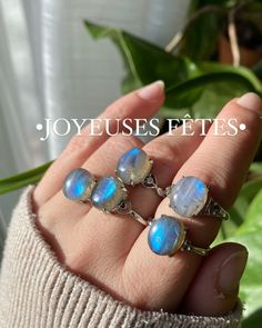 a woman's hand holding three rings with blue and white opalite stones