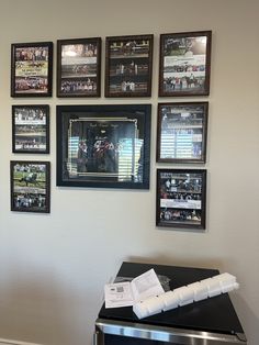 several framed pictures hang on the wall above a trash can