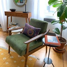 a green chair sitting in front of a window next to a table with a potted plant