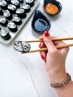 a woman is holding chopsticks near some sushi