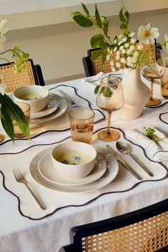 the table is set with white dishes and silverware