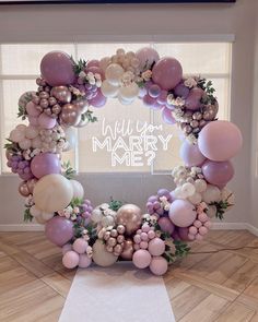 a balloon arch is decorated with balloons and greenery in the shape of a heart