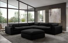 a large black sectional couch sitting in a living room next to a tall glass window