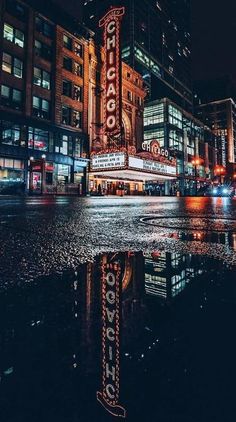 an image of a city street at night with lights and signs on the building's side