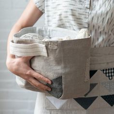 a woman is holding a bag made out of linens and fabric material, with her hands in the pocket