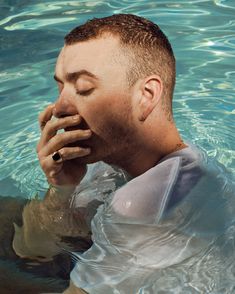 a man is floating in the water with his hand to his mouth and looking up