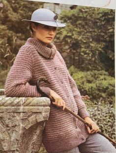 a woman sitting on a stone wall with an umbrella in her hand and wearing a hat