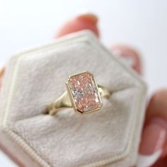 A modern sister to the dainty Stevie ring, this bold tapered band showcases its gorgeous bezel-set pink center stone. Billie is also made in emerald, marquise, and oval. Details: Size 6.5 14k yellow gold 3.80ct radiant lab-grown diamond (Fancy Vivid Pink color, VS1 clarity, IGI certified: 627413274) This ring is ready to ship in size 6.5. If you need the ring resized up to one full size (up or down), please leave a note when you check out and allow 3-5 days for us to resize it for you--we are ha Pink Marquise Engagement Ring, Pink Emerald Engagement Ring, Pink Emerald Cut Engagement Ring, Pink Stone Engagement Rings, Thick Gold Band, Non Traditional Engagement Rings, Radiant Cut Diamond Ring, Pink Wedding Rings, Pink Diamond Engagement Ring