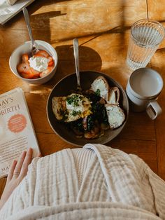 a person laying on the floor next to a bowl of food and a book with eggs in it