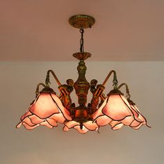 a chandelier hanging from the ceiling with three lamps on it and two people holding hands