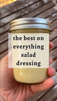 a hand holding a jar with the words, the best on everything salad dressing