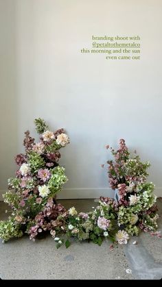 flowers are arranged on the floor in front of a wall with a quote above it