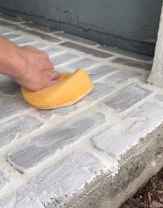 a person using a sponge to clean a brick step with a yellow cloth on it