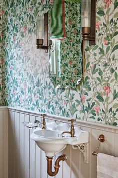 a bathroom with floral wallpaper and two sinks in front of a mirror on the wall