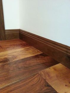 wood flooring in the corner of a room with white walls and wooden trimming