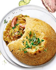 a large piece of bread with meat and vegetables on it sitting on a white plate