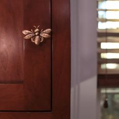 a close up of a wooden cabinet with a bee on the front door knobs