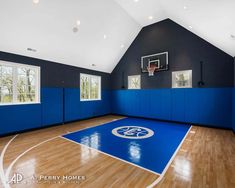 an indoor basketball court with blue walls and hardwood floors is shown in this large home