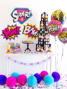 a table topped with lots of balloons next to a cake and confetti bar