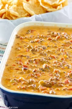 a casserole dish filled with chili cheese and tortilla chips on the side